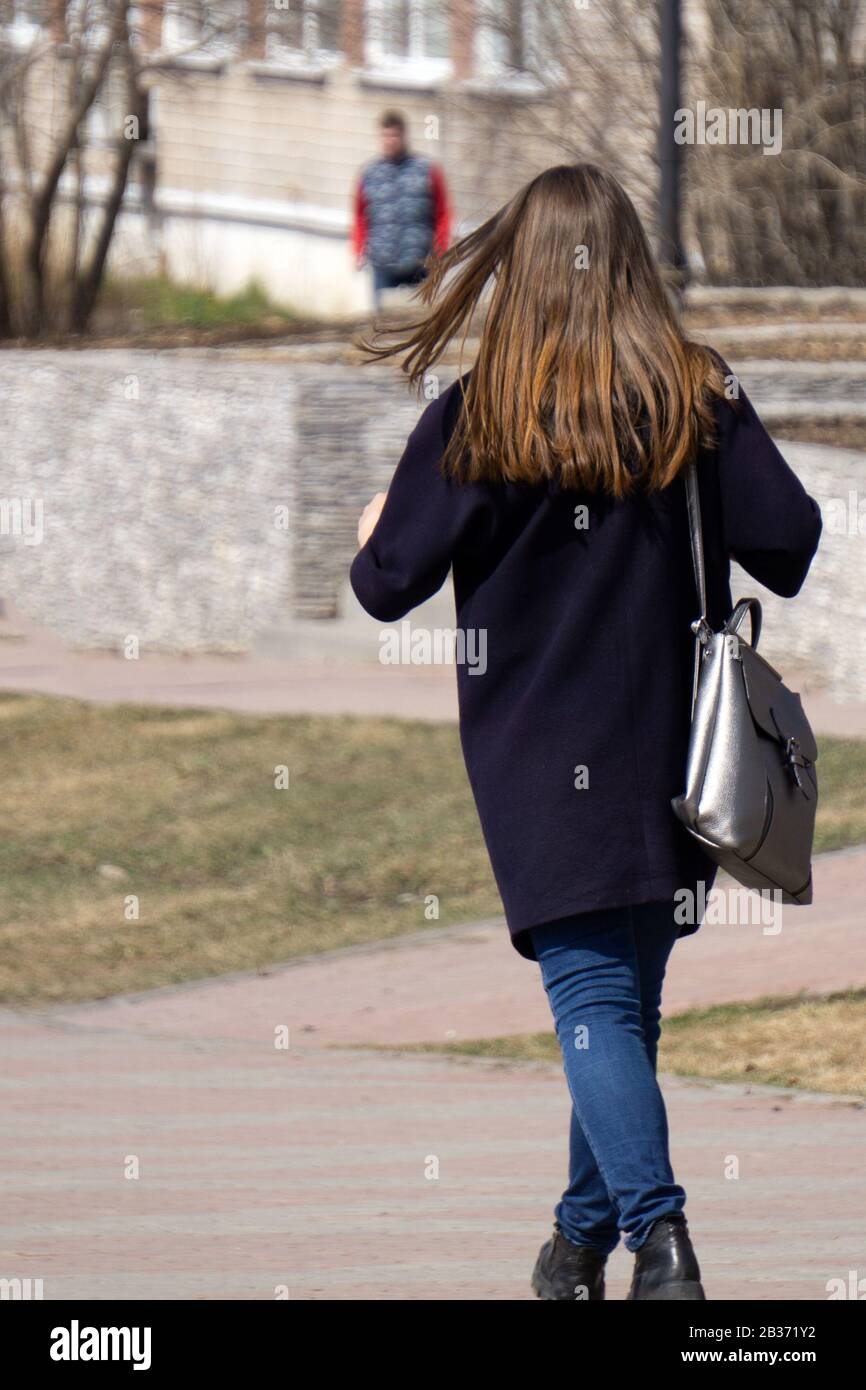 retrato a lo largo de una chica morena con chaqueta y pantalones negros  modernos, posando con la espalda a la cámara sobre fondo gris de estudio  Fotografía de stock - Alamy