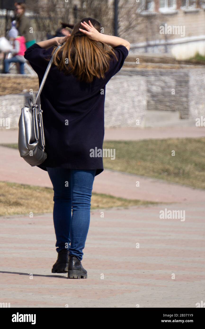 una chica de morena lleva ropa informal, un abrigo negro y botas negras con  jeans, está sosteniendo un libro en sus manos, apoyándola contra la pared  Fotografía de stock - Alamy