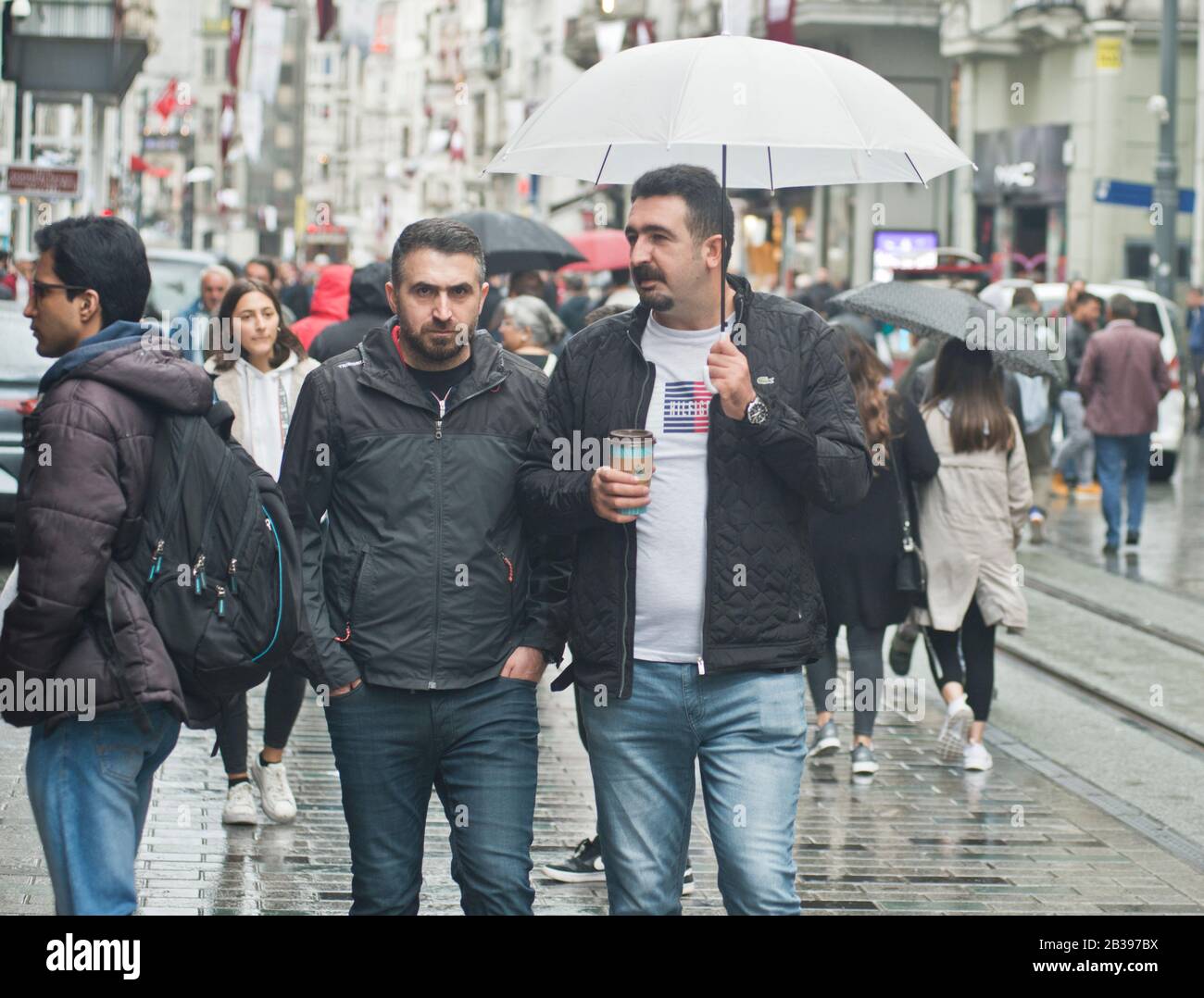 Estambul: Hombres que caminan bajo la lluvia con un paraguas en la avenida Istiklal. Turquía Foto de stock