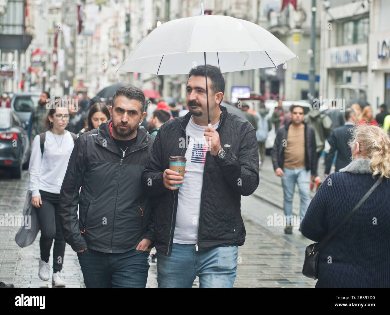 Estambul: Hombres que caminan bajo la lluvia con un paraguas en la avenida Istiklal. Turquía Foto de stock