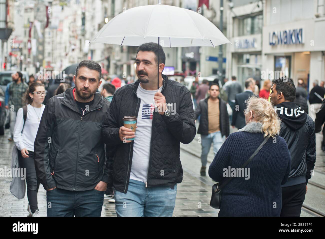 Estambul: Hombres que caminan bajo la lluvia con un paraguas en la avenida Istiklal. Turquía Foto de stock