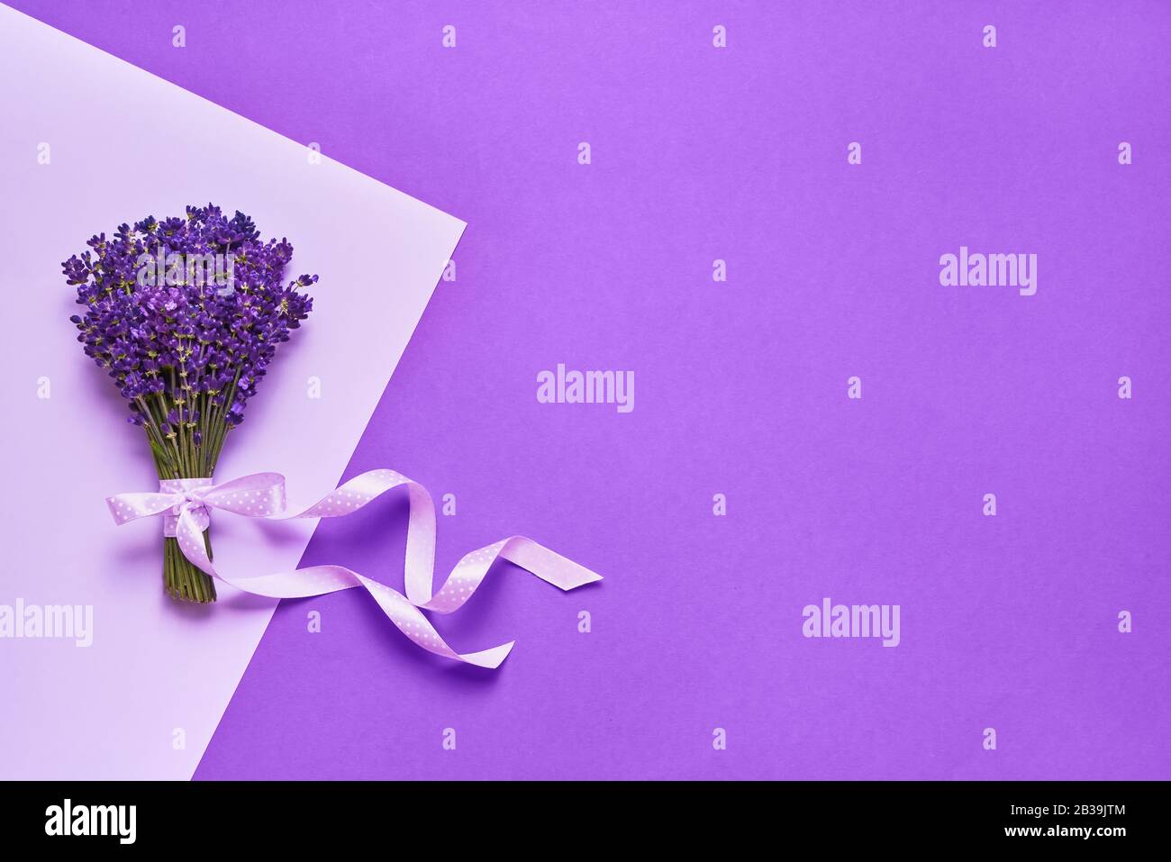 Ramo de hermosas flores de lavanda decoradas con cinta sobre fondo púrpura. Vista superior, espacio de copia para texto. Foto de stock