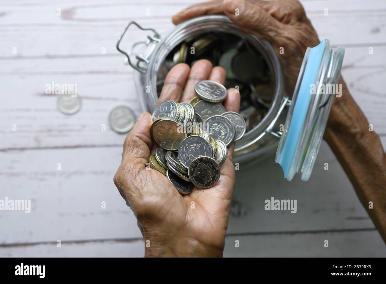 vista superior de las mujeres mayores ahorro monedas en un frasco Foto de stock