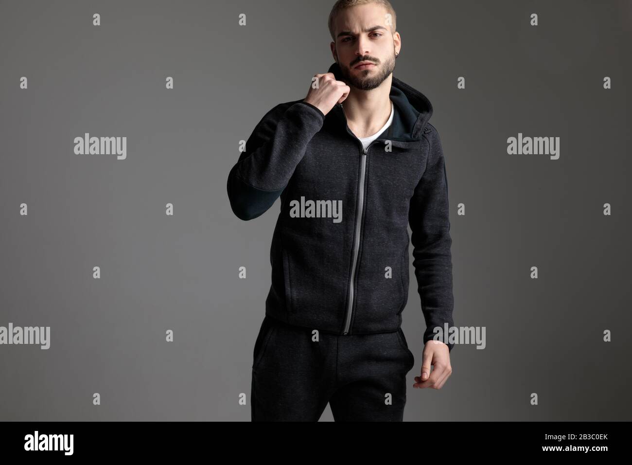 hombre elegante y casual con chándal de pie con un puño sobre fondo gris de  estudio Fotografía de stock - Alamy