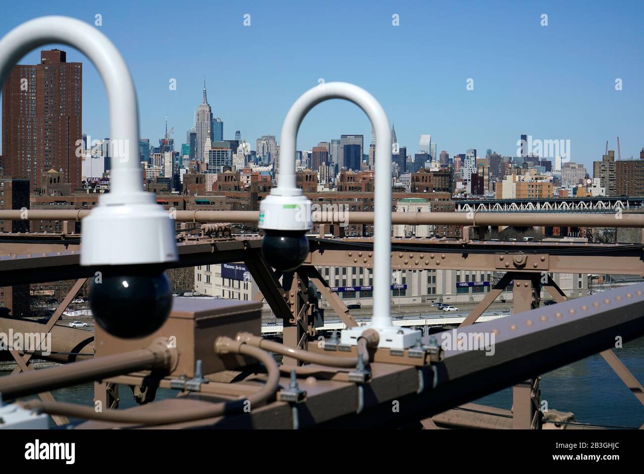 Cámaras de seguridad instaladas en el Puente de Brooklyn con el horizonte de Manhattan y el Empire State Building en el fondo, New York City.USA Foto de stock