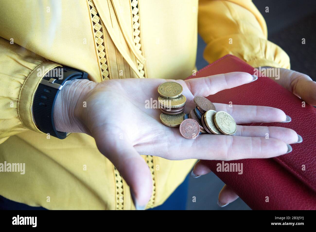 Mujer sosteniendo un pequeño cambio en su palma. Monedas de céntimo de euro sacadas de la cartera. Concepto de dinero. Escasez de recursos. Foto de stock