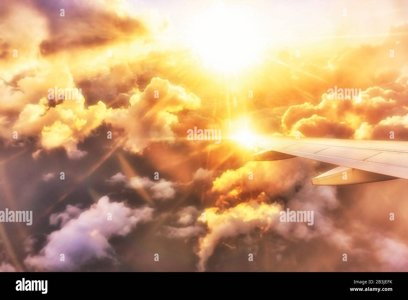 Vista en un brillante ala del avión al atardecer sobre las nubes Foto de stock