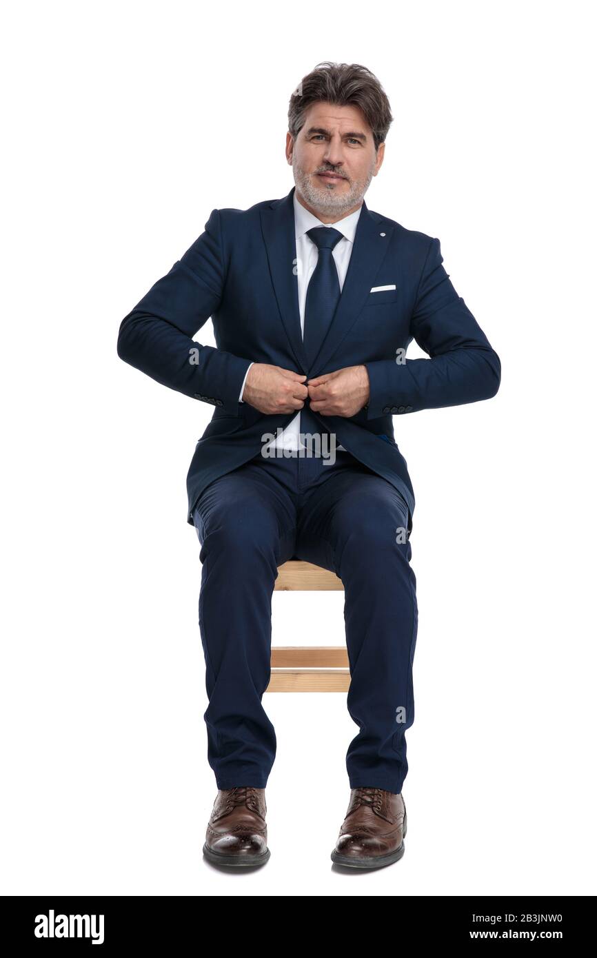 encantador hombre de negocios formal con traje azul marino está sentado y  arreglando su chaqueta feliz sobre fondo blanco de estudio Fotografía de  stock - Alamy