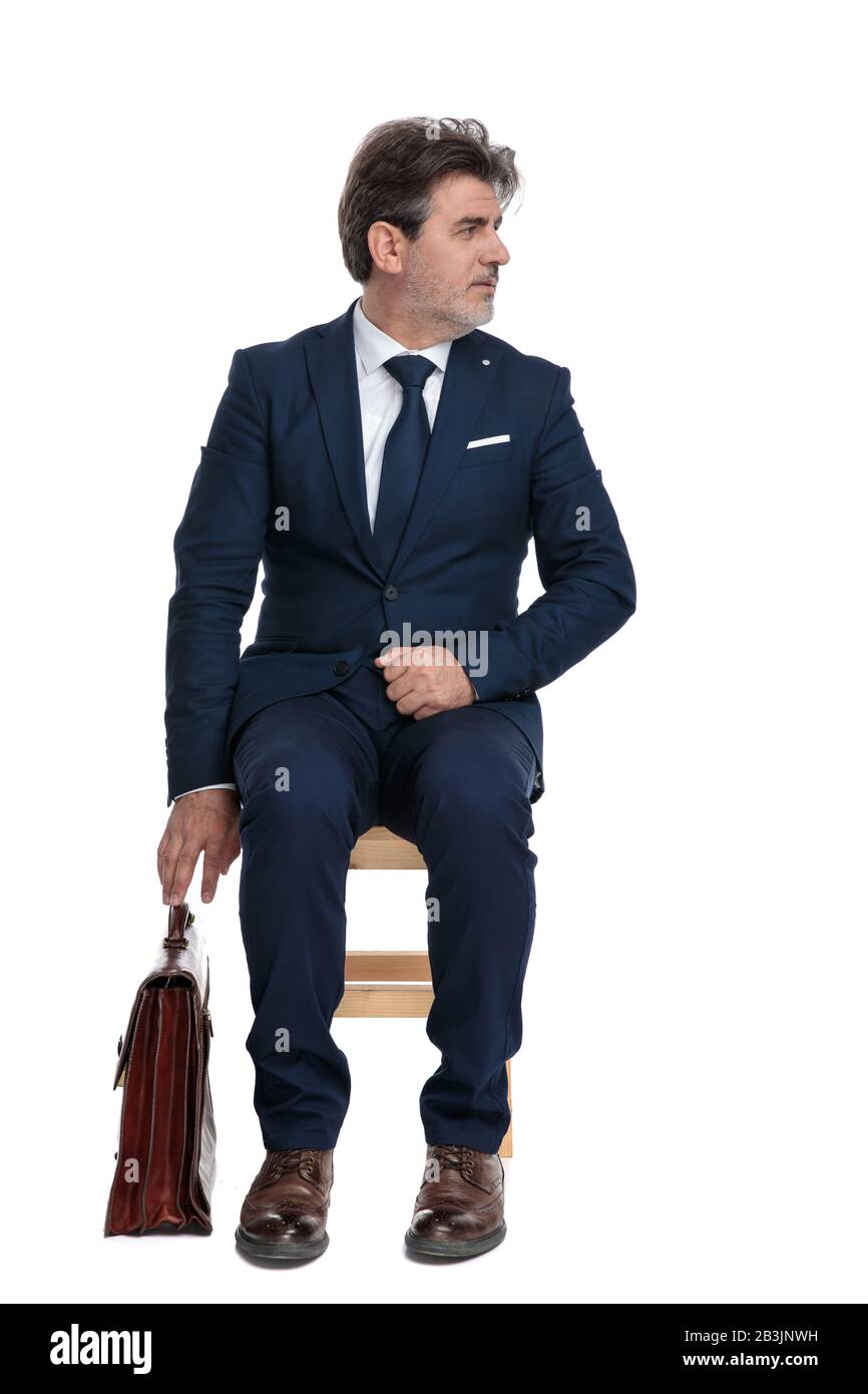 dos Retirado Unirse elegante hombre de negocios formal con traje azul marino sentado listo para  agarrar su maletín y mirar a un lado serio sobre fondo blanco de estudio  Fotografía de stock - Alamy