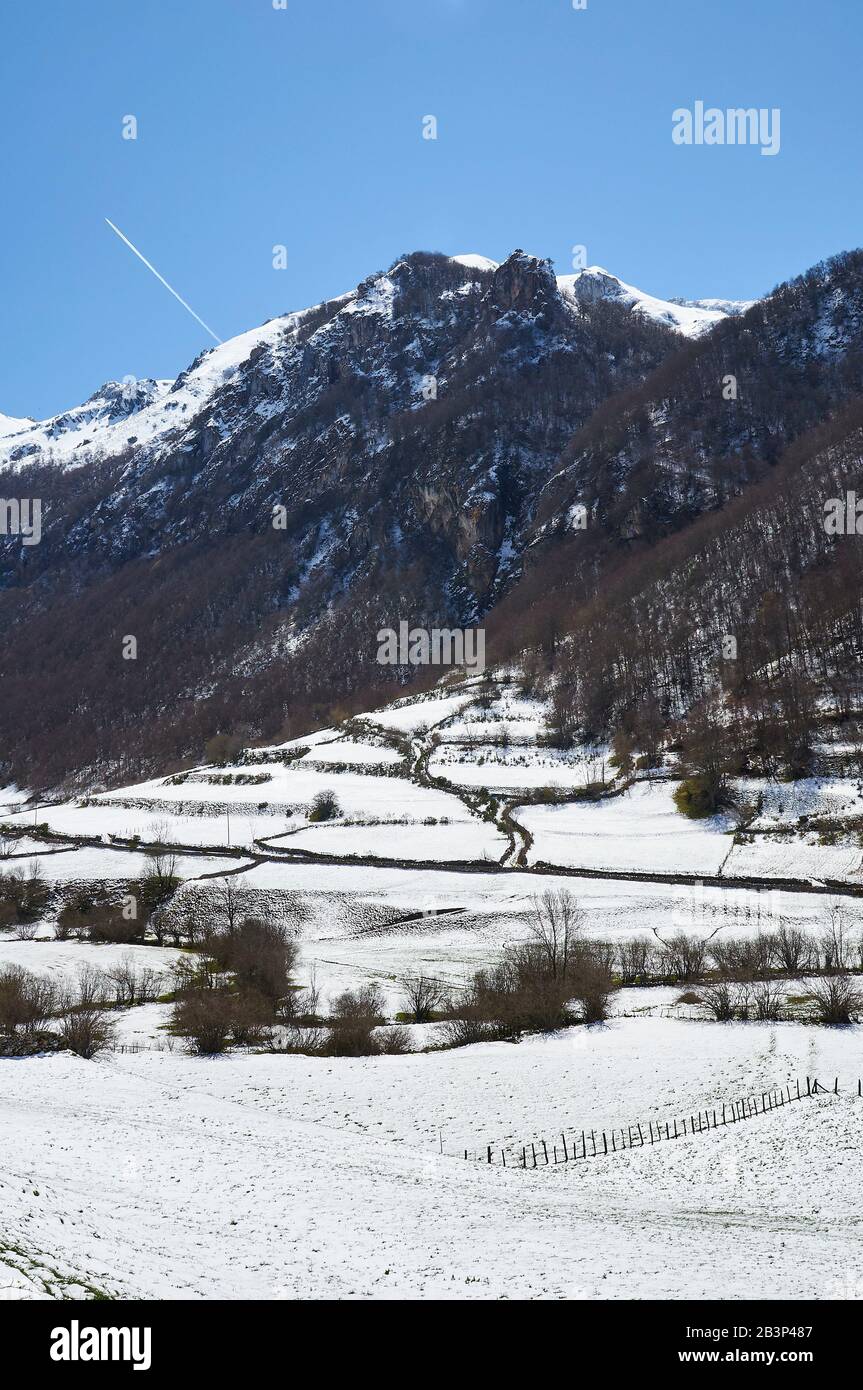 Paisaje nevado en Valle del Lago desde PR.AS-15 sendero con montañas nevadas en la distancia (Valle del Lago, Parque Natural de Somiedo, Asturias, España) Foto de stock