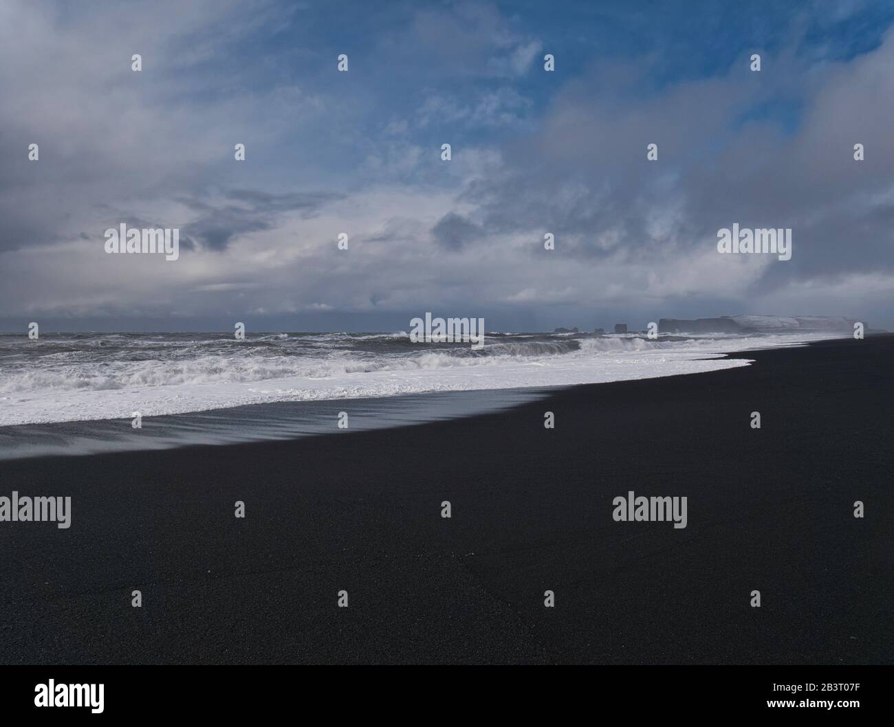Hermosa sección costera de la playa de arena negra en Islandia con nubes Foto de stock