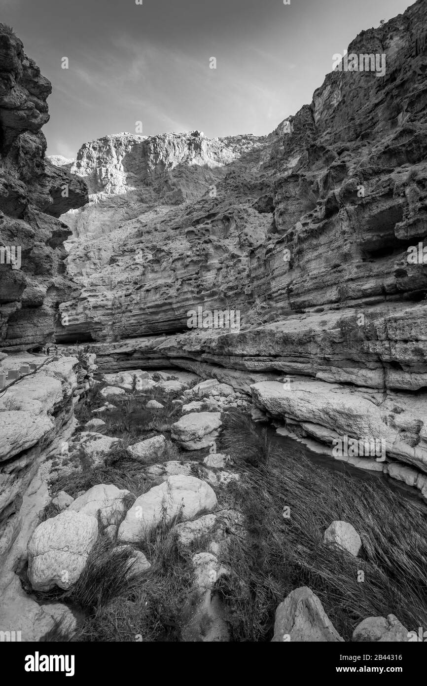 Blanco y negro del paisaje cañón del río Wadi Shab con acantilados rocosos y fuentes de agua verde - Sultanato de Omán Foto de stock