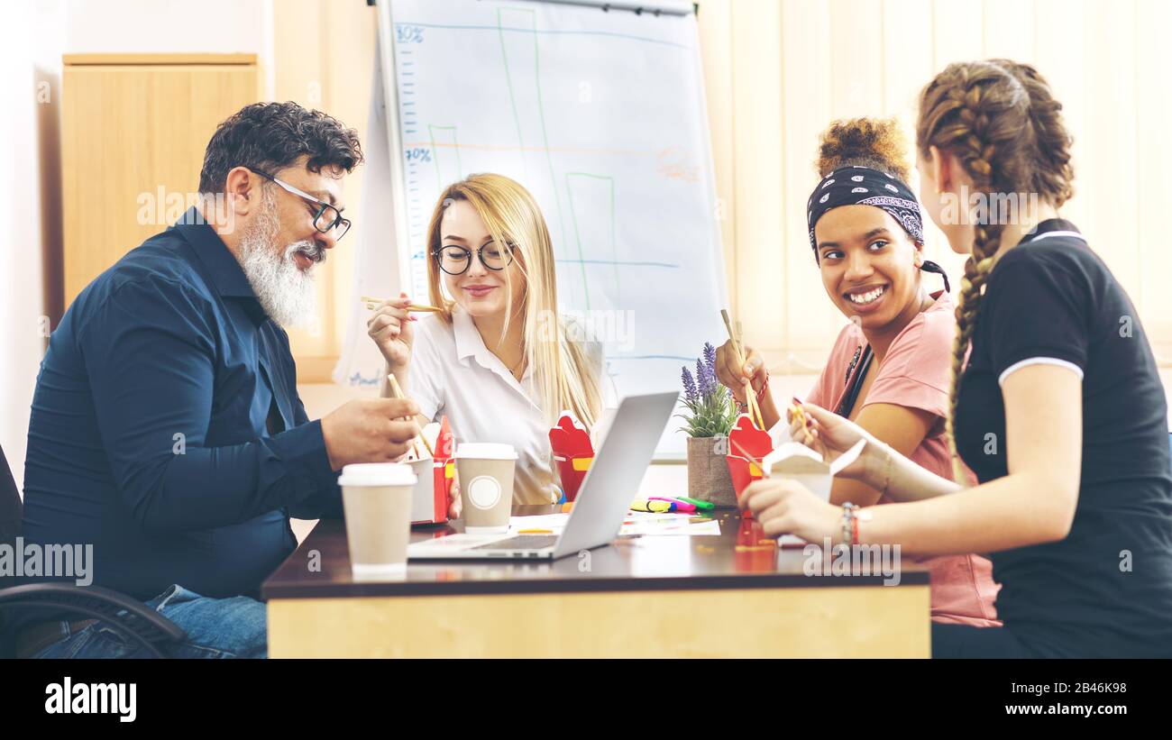 Multi-étnico grupo empleados disfrutar de comida para llevar la conversación amistosa en Office Foto de stock