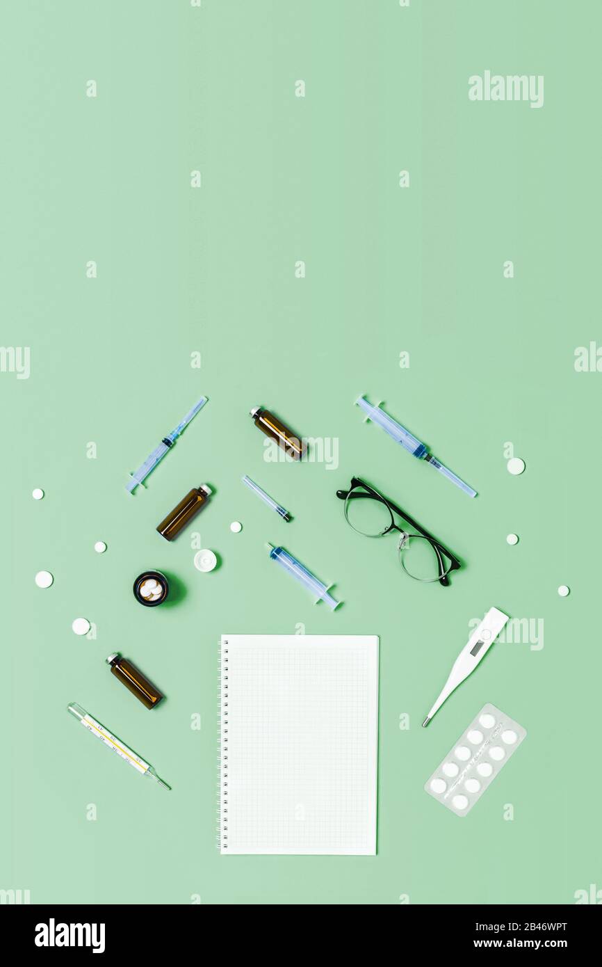 Fondo médico verde menta con diferentes accesorios: Estetoscopio, termómetro, jeringa, tabletas y bloc de notas. Foto de stock