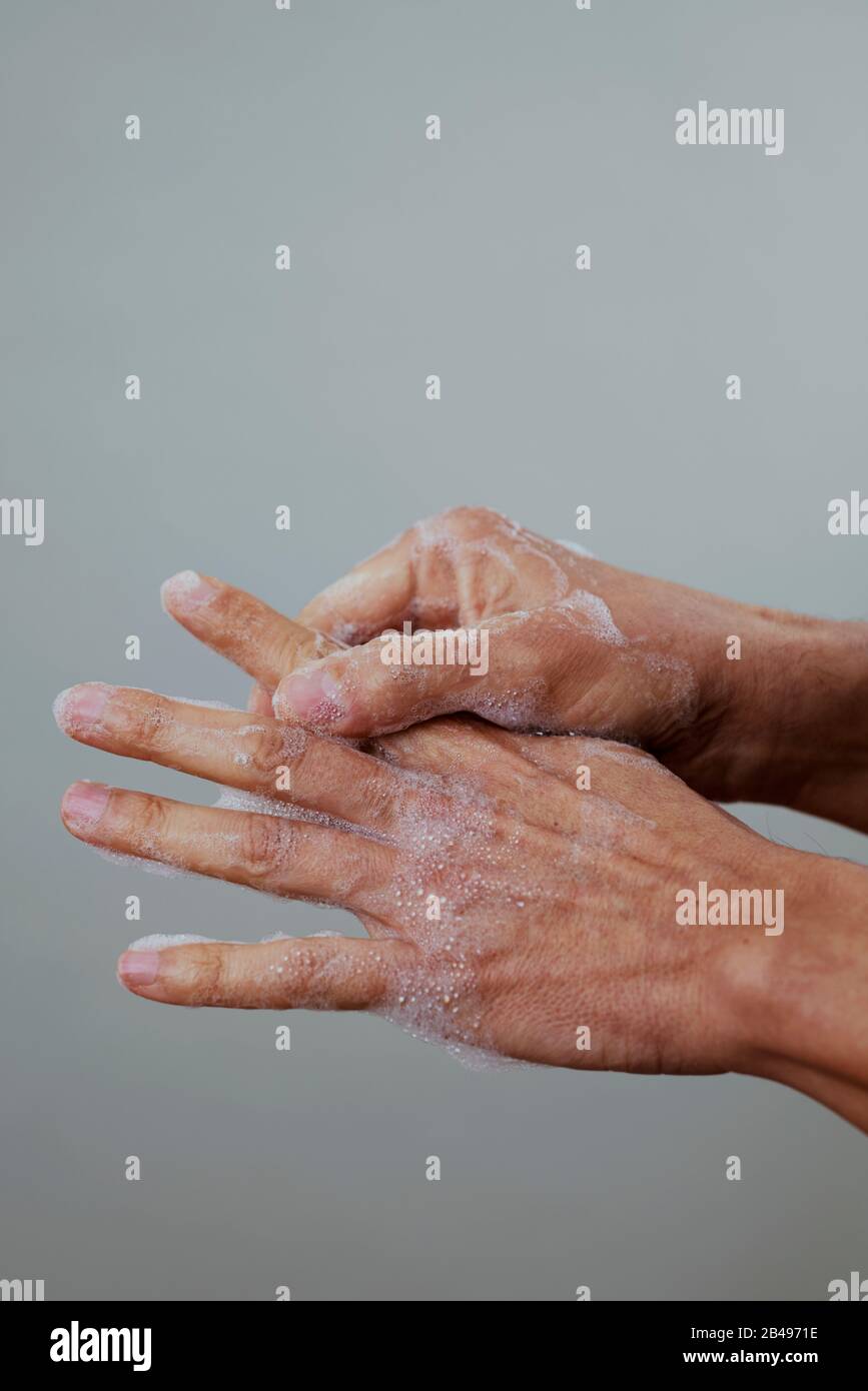 cierre de un hombre caucásico lavándose las manos con jabón sobre un fondo gris pálido Foto de stock