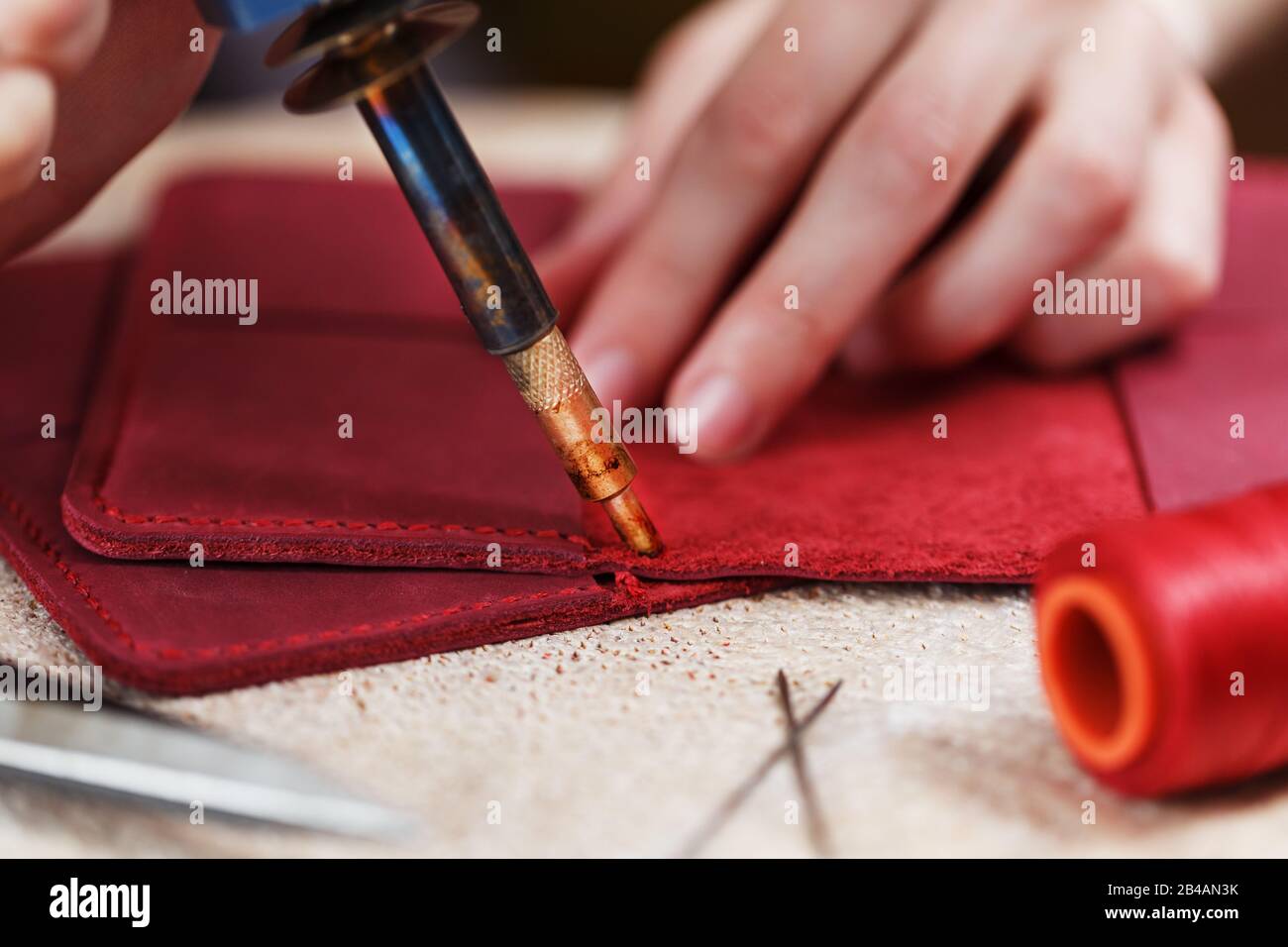 Un artesano de cuero trabaja con cuero. Siesta artículos de cuero. Hacer  cosas hechas a mano. Las manos de las mujeres con una aguja, hilo, tijeras  y soplete. Clo Fotografía de stock -
