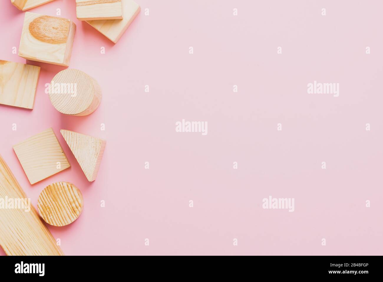 Juguetes de madera para niños sobre un concepto de fondo rosa cero al oeste. Marco de cubos en desarrollo. Espacio de copia. Diseño plano de vista superior. Foto de stock