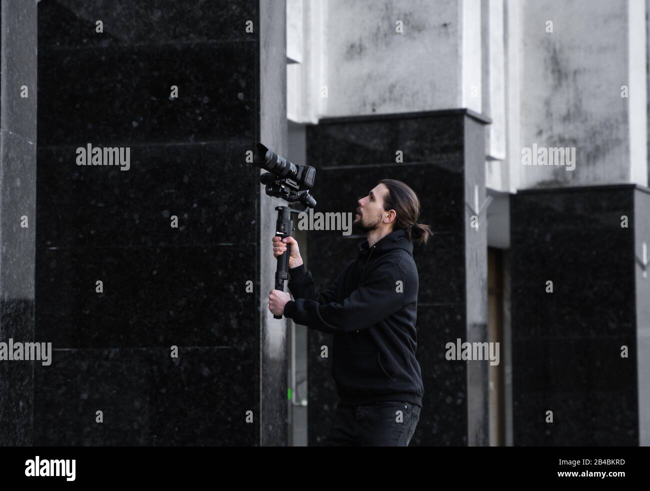 Joven videógrafo profesional que sostiene la cámara profesional en el estabilizador de 3 ejes. El equipo ayuda a hacer video de alta calidad sin temblar Foto de stock