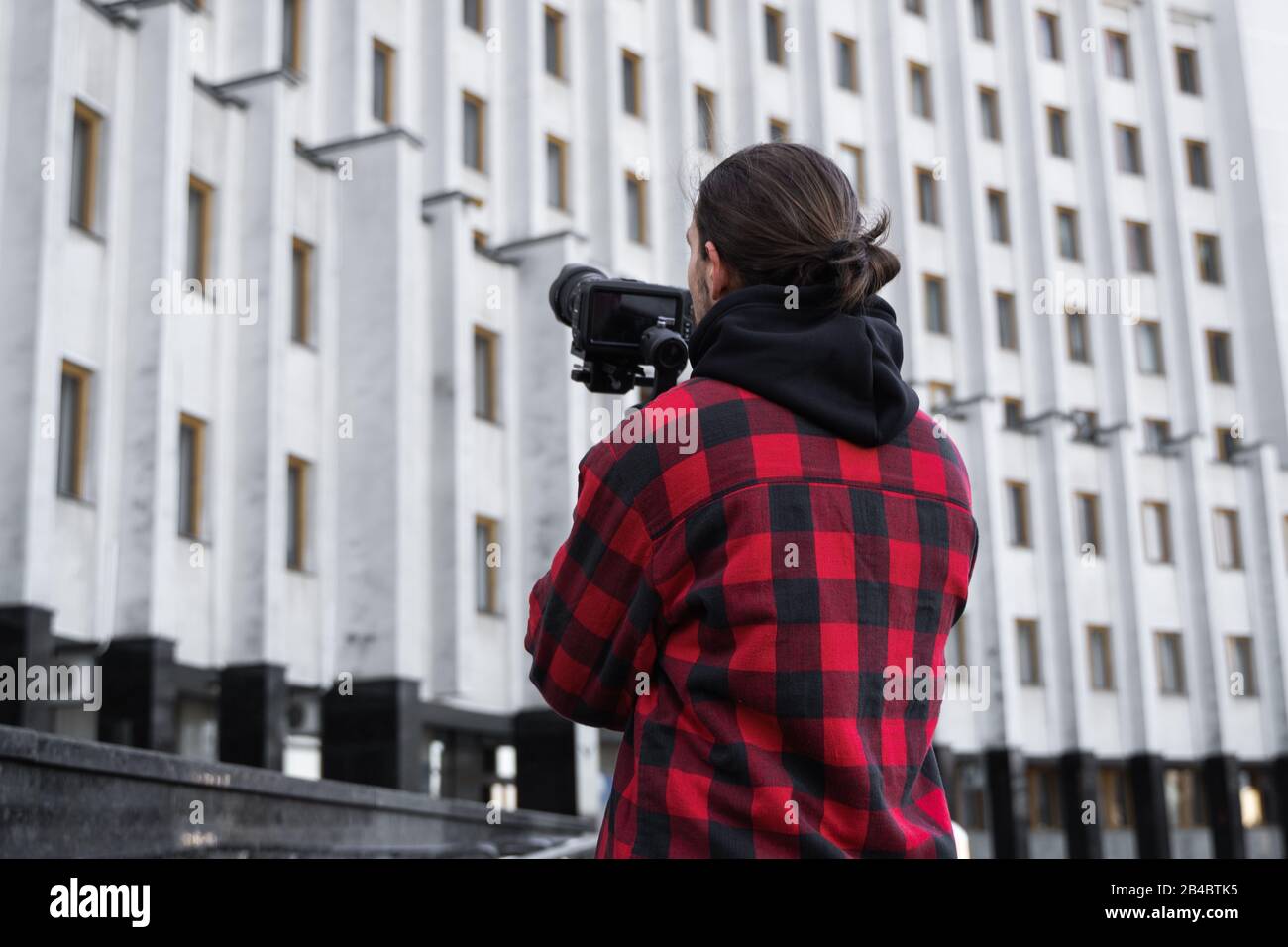 Joven videógrafo profesional que sostiene la cámara profesional en el estabilizador de 3 ejes. El equipo profesional ayuda a crear vídeo de alta calidad sin Foto de stock