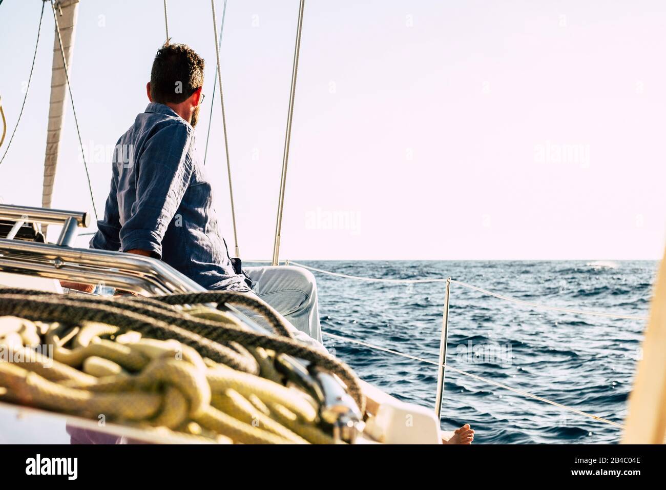 Hombre libre disfrutando de la actividad de ocio al aire libre en un barco de vela con el océano azul alrededor - concepto de vacaciones de verano de lujo - gente feliz navegando con la naturaleza y buen tiempo Foto de stock