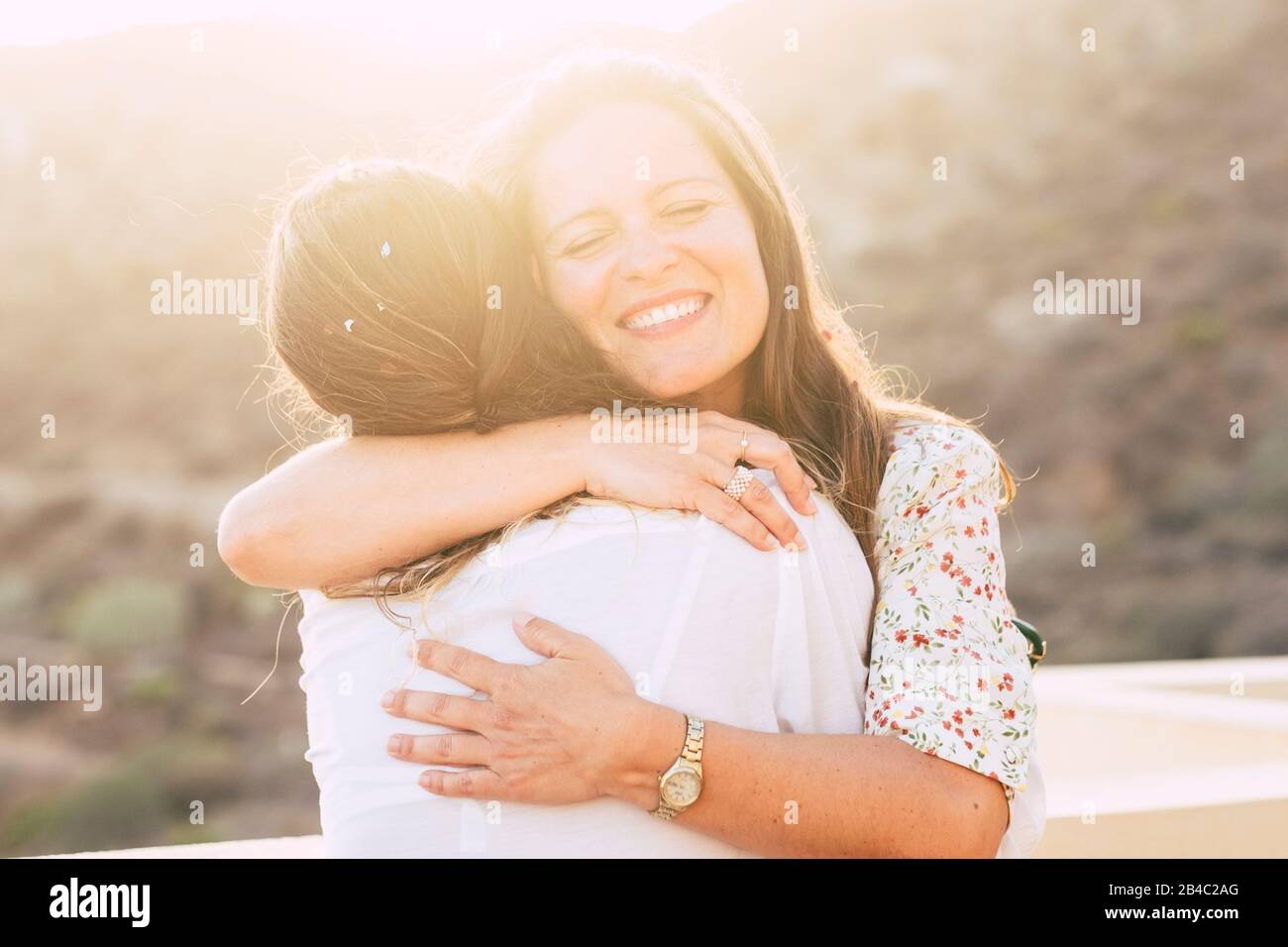 Concepto de amor y amistad con pareja de mujeres jóvenes amigos abrasando y sonriendo con amor - diversidad para la gente caucásica - amor alternativo - sol en contraluz con efecto de luz Foto de stock