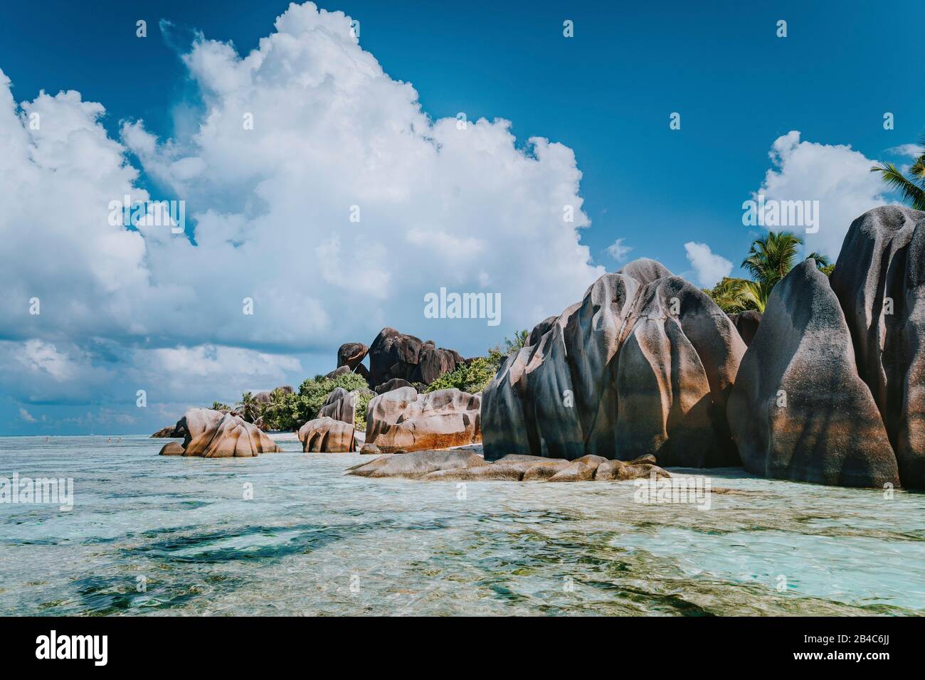 Famosas rocas de granito en la laguna con aguas poco profundas del océano y nubes blancas en la increíble playa tropical Anse Source D'Argent, la Digue Seychelles. Concepto de viaje exótico de lujo. Foto de stock