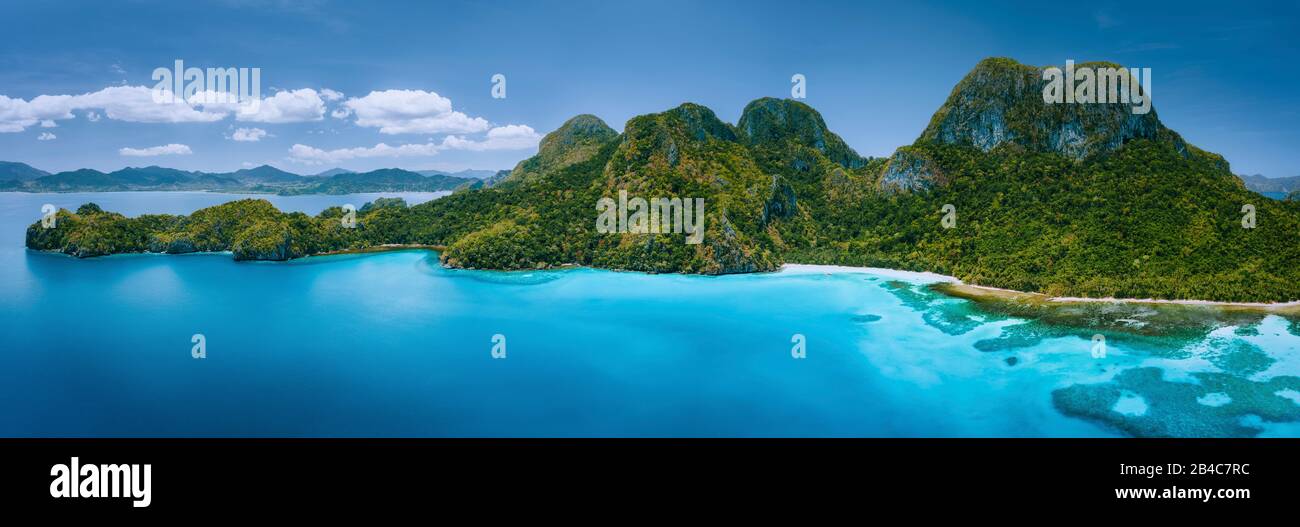 Vista panorámica aérea de drone de isla tropical deshabitada con montañas escarpadas, selva tropical, playas de arena rodeadas por el océano azul. Foto de stock
