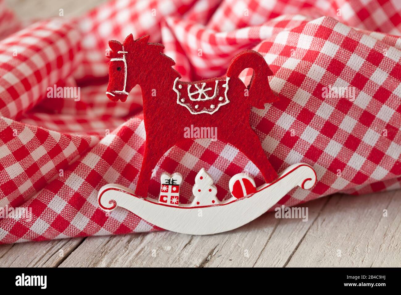 Navidad decorativa todavía vida estilo nórdico con caballo mecedora ornamento a través de un rojo-blanco de cuadros tejido Foto de stock