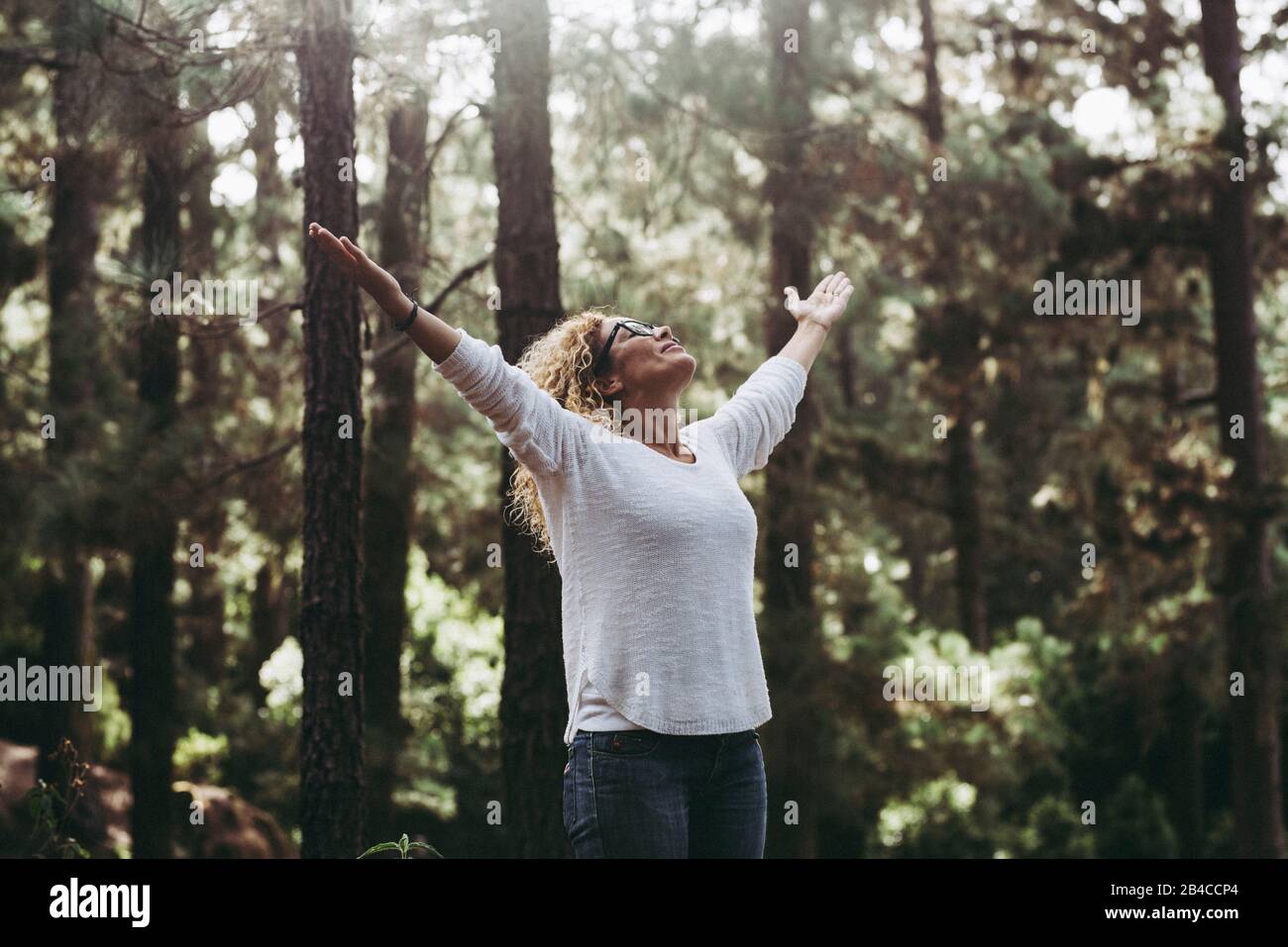 Salvar el planeta para un mejor concepto de futuro limpio y verde - gente caucásica joven mujer abriendo los brazos en el bosque para detener la deforestación y ayudar al mundo Foto de stock
