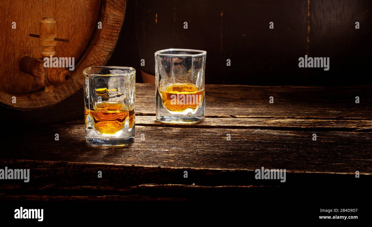Barril de whisky y vasos de whisky en una mesa de madera Foto de stock