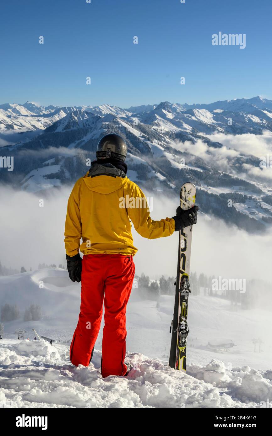 Esquiador parado en la pista de esquí que sostiene el esquí, vista a la distancia, paisaje nevado de la montaña, la cumbre Hohe Salve, SkiWelt Wilder Kaiser Brixenthal Foto de stock