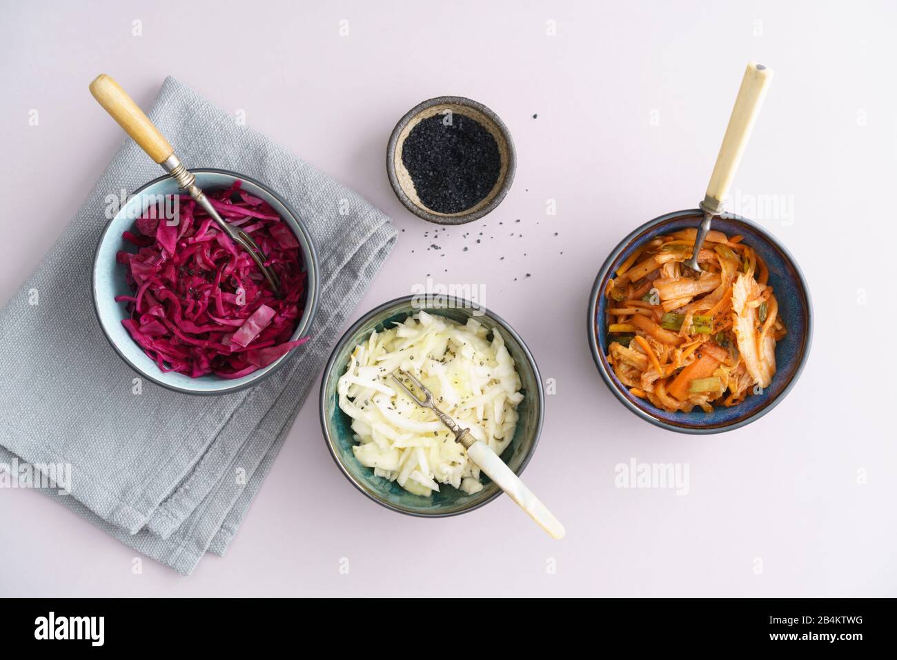 Repollo blanco, kimchi y repollo rojo fermentados, encurtidos, servidos en cuencos pequeños Foto de stock