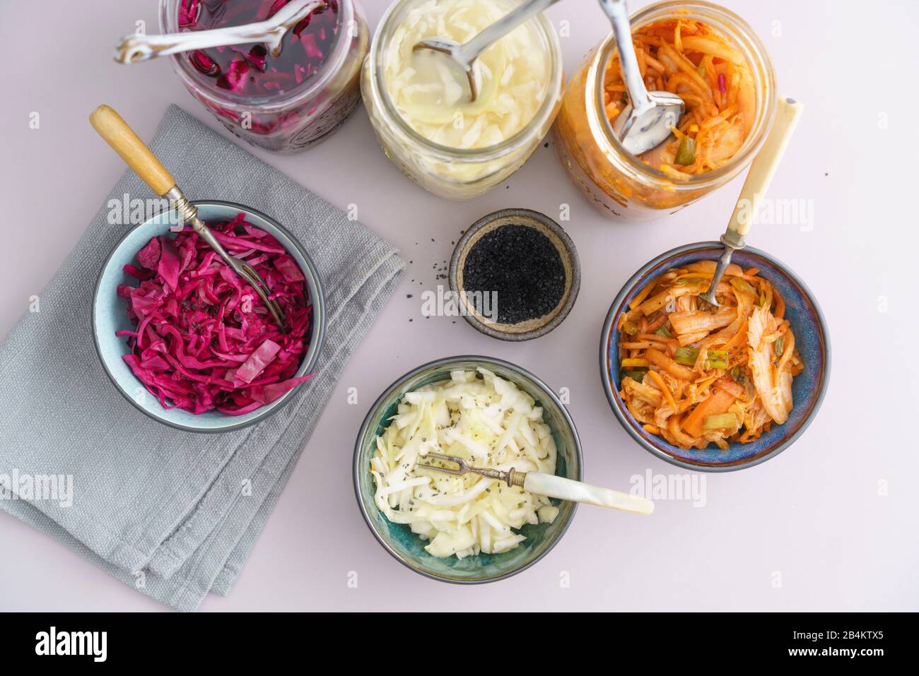 Repollo blanco, kimchi y repollo rojo fermentados, encurtidos en tarros de conservación, servidos en tazones pequeños Foto de stock