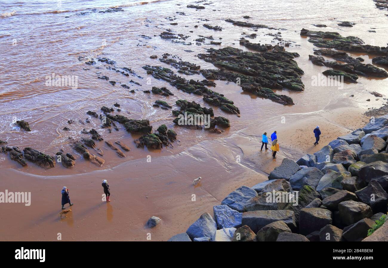 La gente camina por la playa de arena durante la marea baja en la ciudad de Sidmouth, Devon Foto de stock
