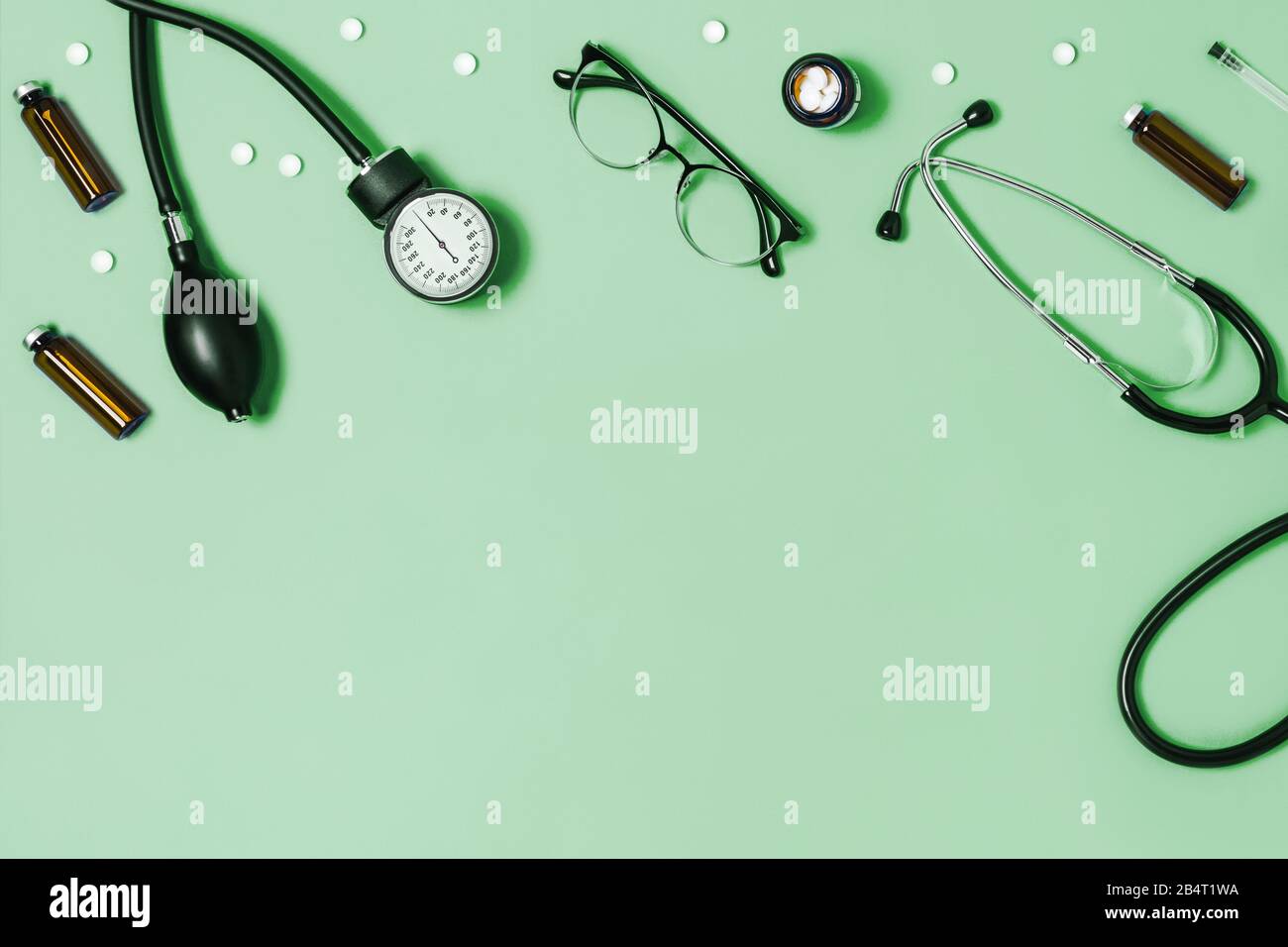 Fondo médico verde menta con diferentes accesorios: Estetoscopio, termómetro, jeringa y tabletas. Foto de stock