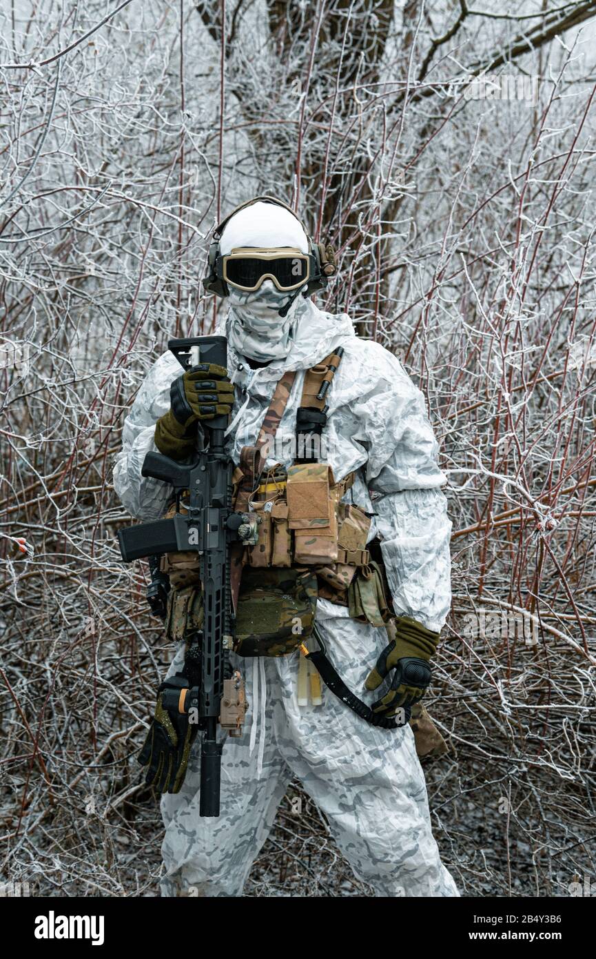 Militar en traje de camuflaje blanco con machinegun. Soldado en el fondo  del territorio del bosque de invierno. Foto vertical Fotografía de stock -  Alamy