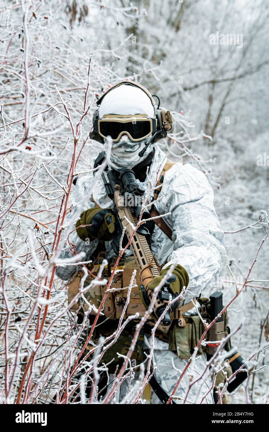 Militar en traje de camuflaje blanco con machinegun. Soldado en el fondo  del territorio del bosque de invierno. Foto vertical Fotografía de stock -  Alamy