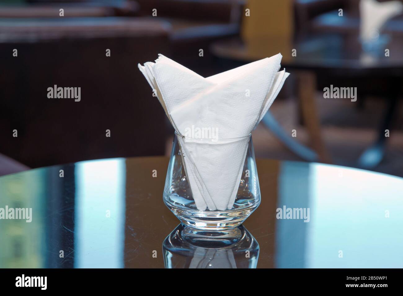 Imagen desenfoque - Blanca servilleta de papel se coloca en un vaso sobre  la mesa en la sala de banquetes . Hotel mesa de comedor con servilletas  decorativas, vajillas de vidrio en