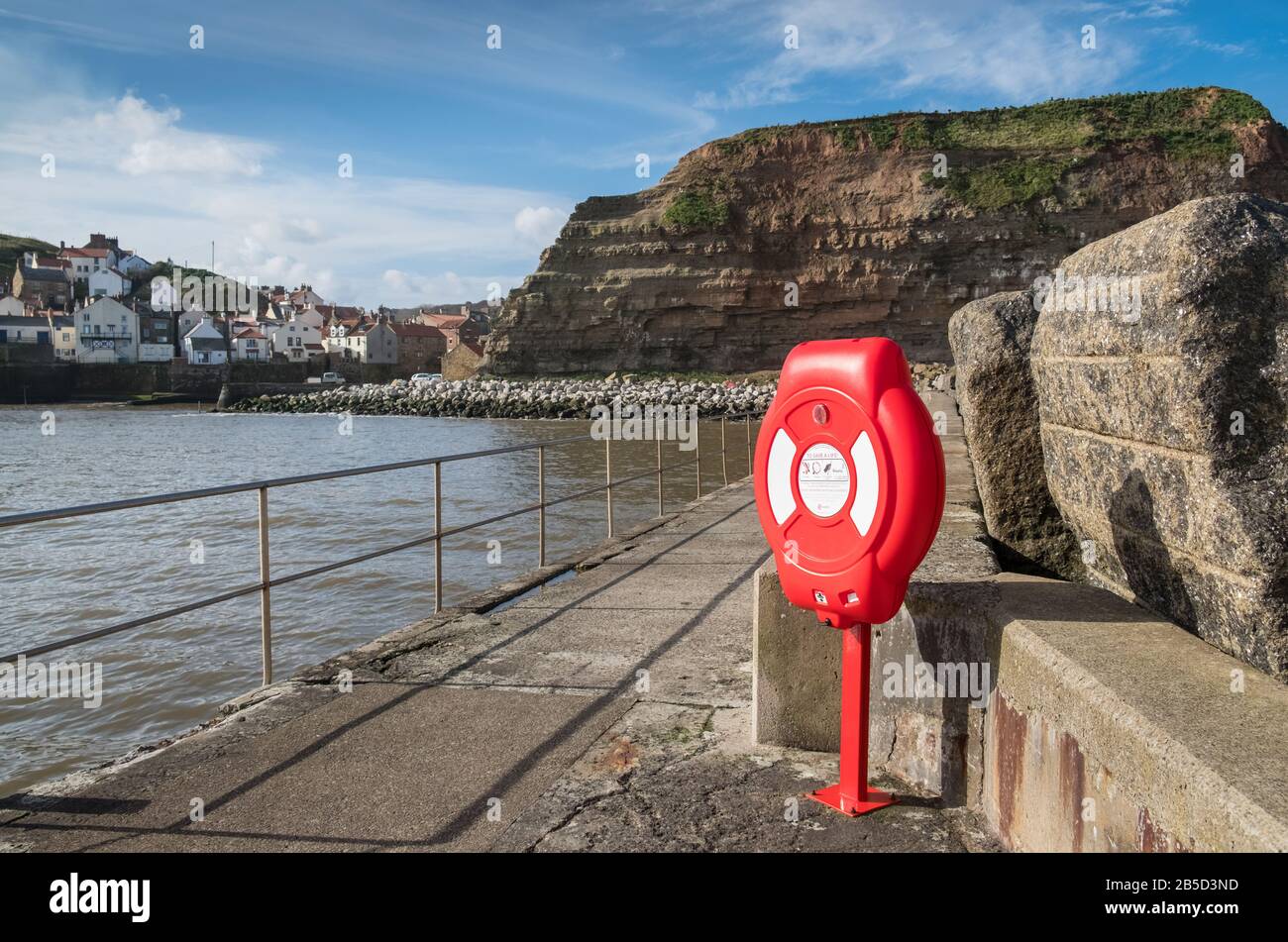 Un anillo de boya de vida para emergencias acuáticas situado en el bonito puerto costero de Staithes, un pintoresco pueblo en la costa de North Yorkshire, Reino Unido Foto de stock