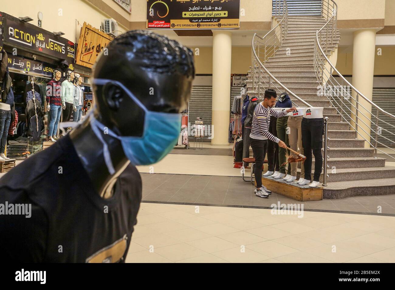 El 8 de marzo de 2020, se exhibió maniquíes con máscaras faciales fuera de una tienda de ropa, en la Franja de Gaza, para difundir la conciencia sobre la enfermedad coronavirus COVID-19, Foto de stock