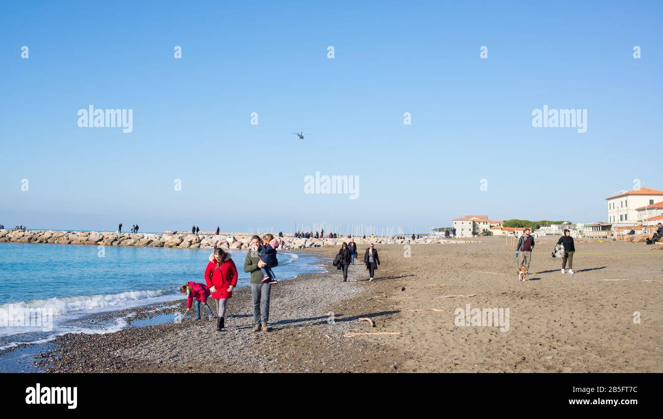 Cecina, Toscana, Italia - 2020 de enero: Invierno escena costera en Toscana con la gente que disfruta del soleado clima italiano en una playa de arena Foto de stock