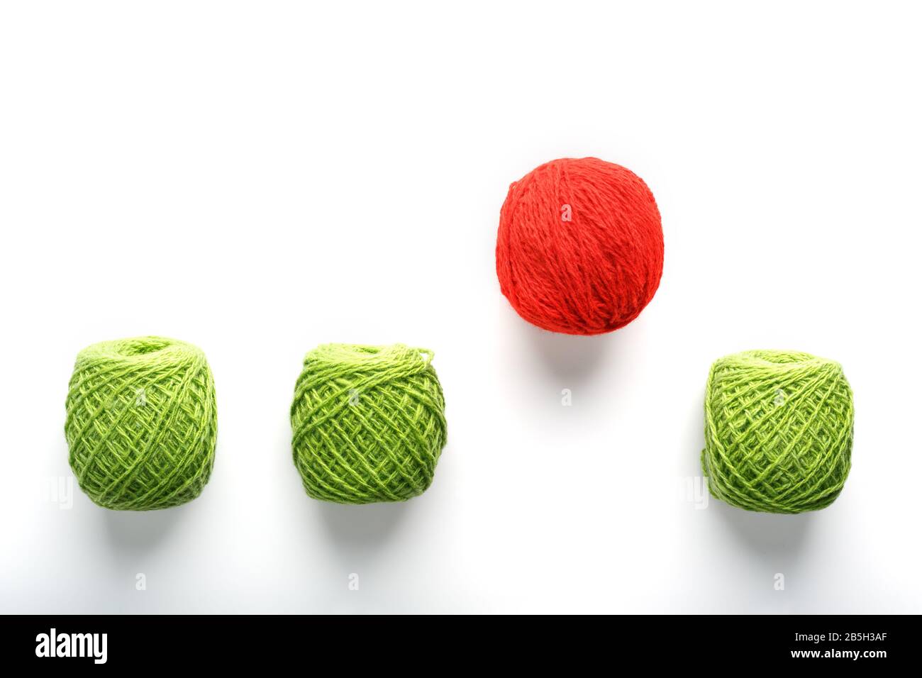Una exclusiva bola roja salta de una fila de bolas de lana idénticas.  Concepto abstracto de liderazgo, Sea diferente. Trabajo en equipo en el  negocio y requisitos previos para Fotografía de stock -