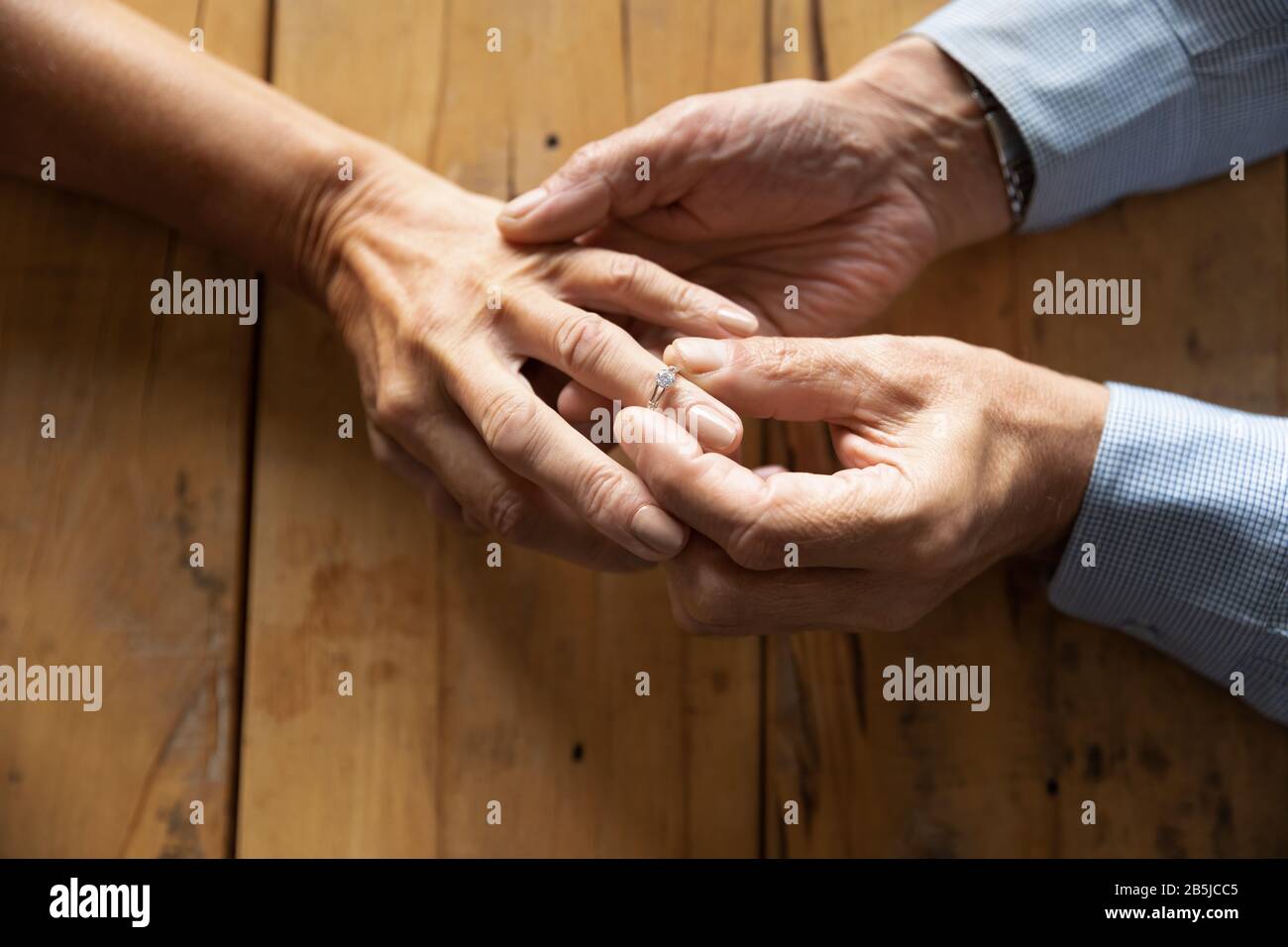 El anciano puso el anillo de boda en la mano de la mujer de mediana edad Foto de stock