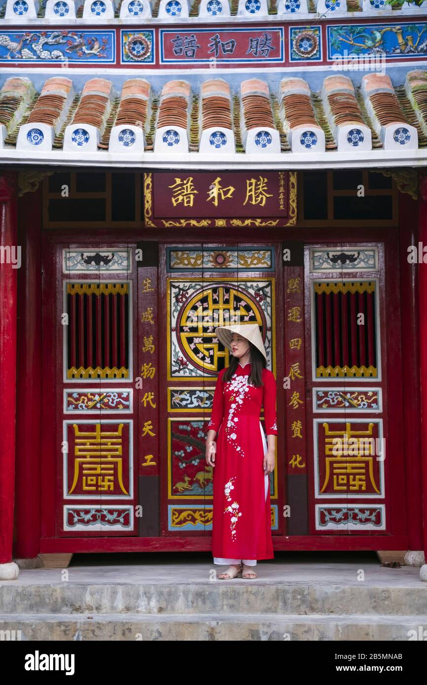 Una joven vietnamita que viste un vestido tradicional de Ao Dai en las calles de la vieja Hoi An Foto de stock