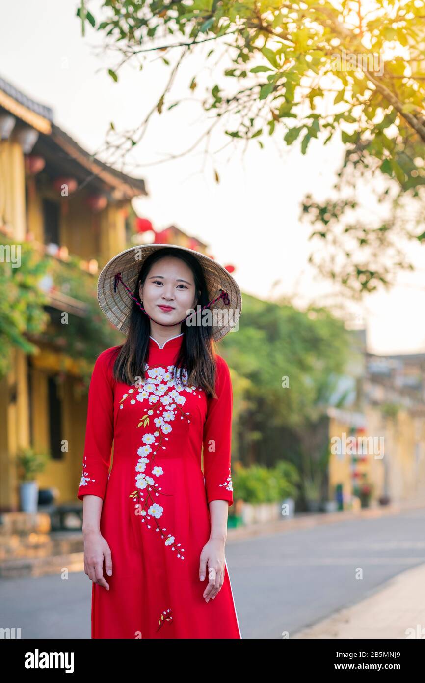 Una joven vietnamita que viste un vestido tradicional de Ao Dai en las calles de la vieja Hoi An Foto de stock