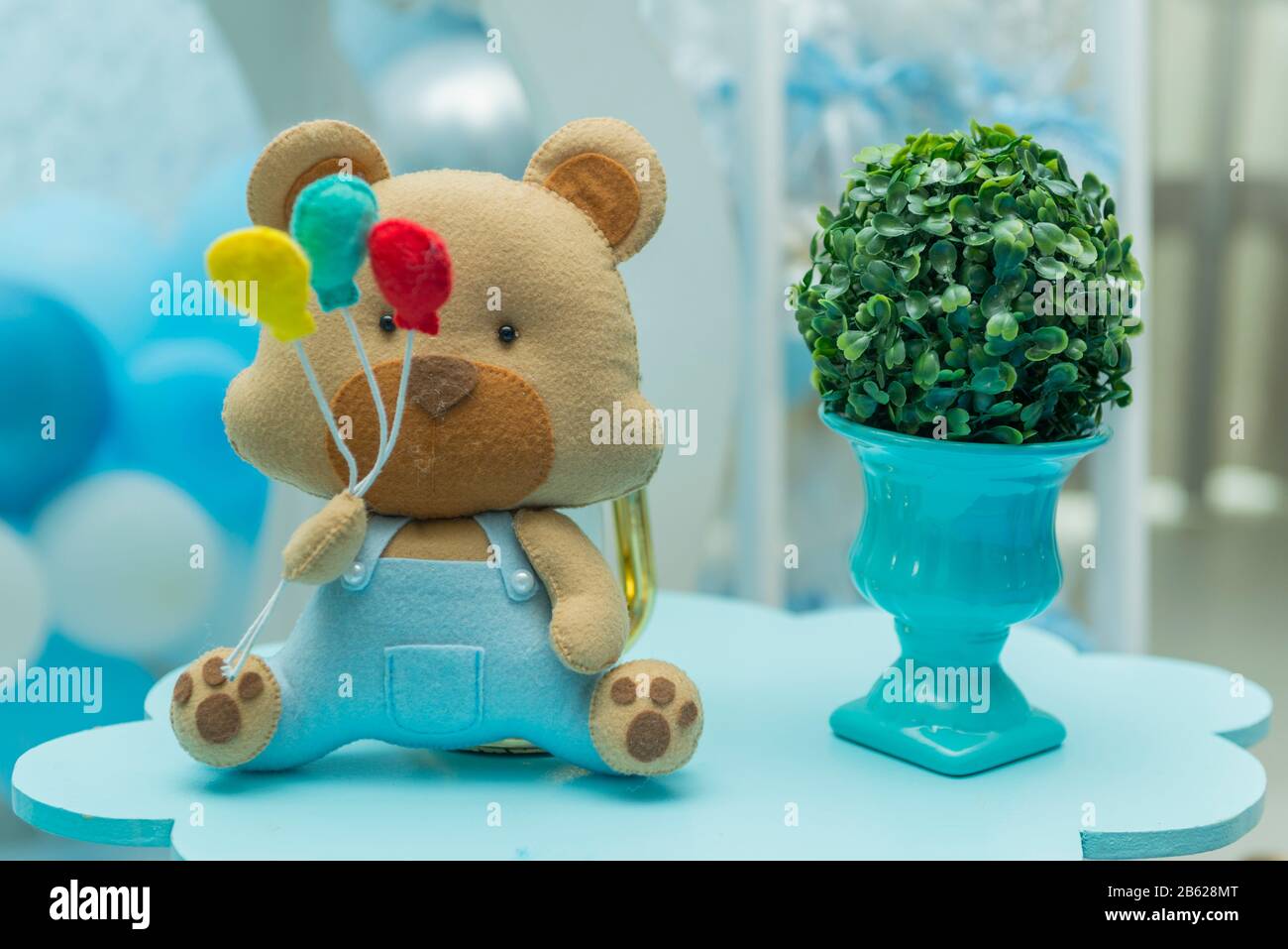 Decoración de fiesta con osito de peluche con globos coloridos junto al  lujoso jarrón de cerámica azul con fondo difuminado Fotografía de stock -  Alamy