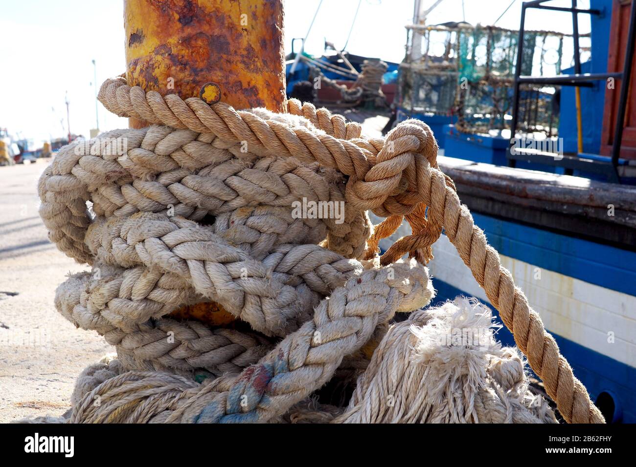 Soga alrededor de un bollard en un puerto pesquero Foto de stock
