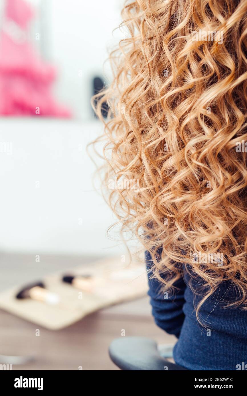 Largo cabello rubio femenino rizado durante el cabello con rizador, primer  plano, sobre fondo interior de barbero Fotografía de stock - Alamy