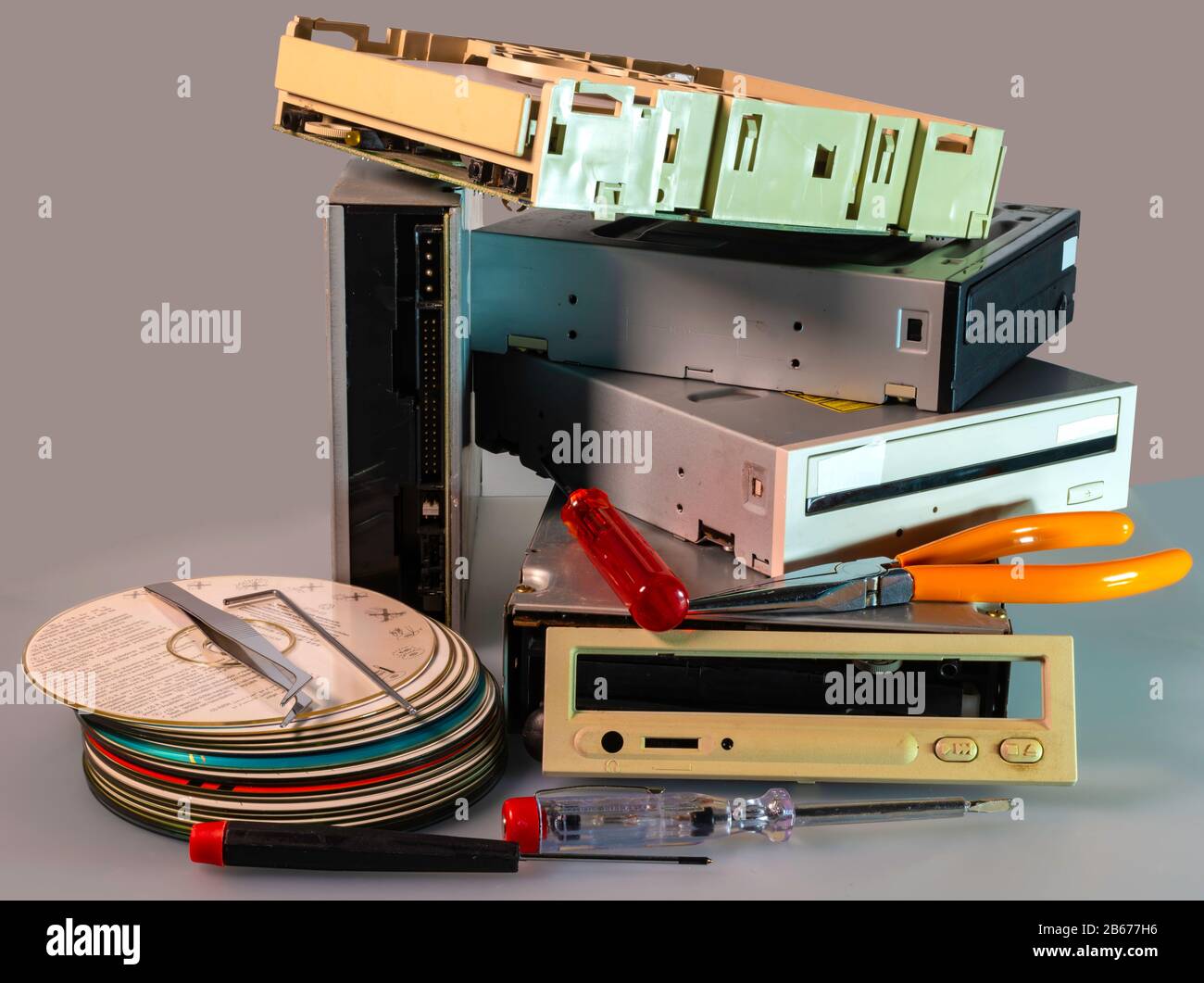 Pila de unidades de disco duro SATA, ATA antiguas y cd de controladores desmontados. En un disco de cartón muestra advertencias en varios idiomas para su uso en CD regrabable wri Foto de stock