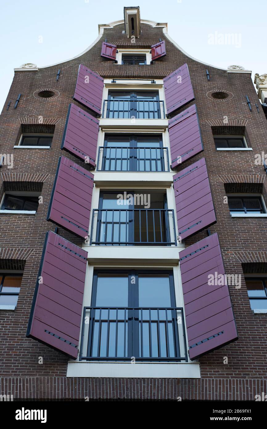 Persianas de color púrpura en cinco pisos en la típica casa de Amsterdam con tejados en Herengracht Foto de stock